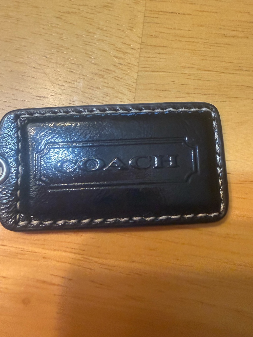 The Coach black patent Tag Fob Handbag Charm is a stylish accessory designed